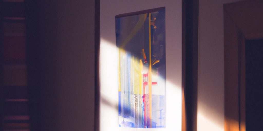 Light shining on a framed colored pencil drawing hanging on a wall